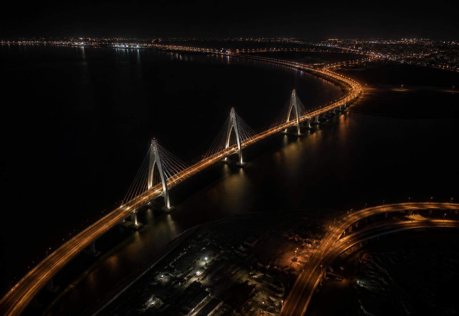Aerial night view of a coastal city bridge and infrastructure